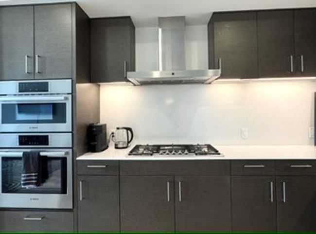 Kitchen with wall chimney exhaust hood, appliances with stainless steel finishes, and modern cabinets | Image 19