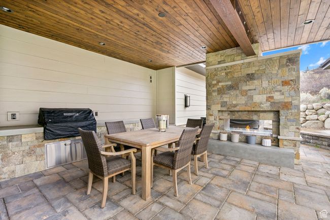 View of patio / terrace with an outdoor stone fireplace, outdoor dining area, and area for grilling | Image 99