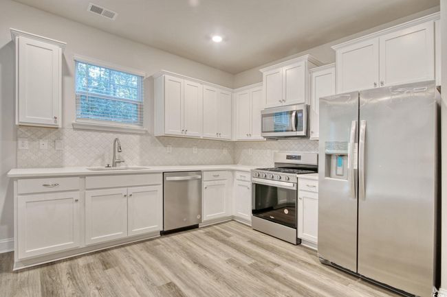 Kitchen featuring white cabinets, stainless steel appliances, and light hardwood / wood-style flooring | Image 16