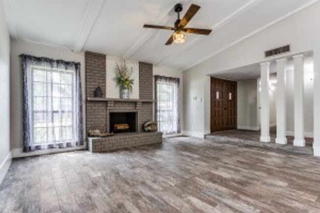 Unfurnished living room featuring wood finished floors, a healthy amount of sunlight, lofted ceiling with beams, and visible vents | Image 8