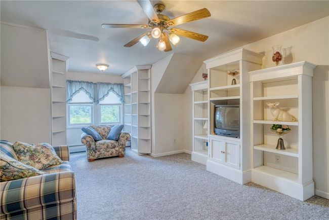 Living area featuring baseboard heating, light colored carpet, and ceiling fan | Image 23
