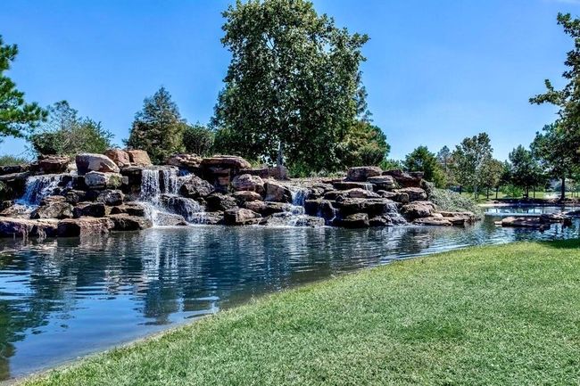 The community tranquil pond features cascading waterfalls and lush greenery, offering a peaceful and scenic view ideal for relaxing outdoor living. | Image 37