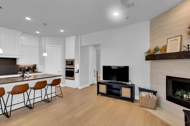 Kitchen featuring dark countertops, a kitchen bar, light wood-style floors, white cabinetry, and stainless steel appliances | Image 7