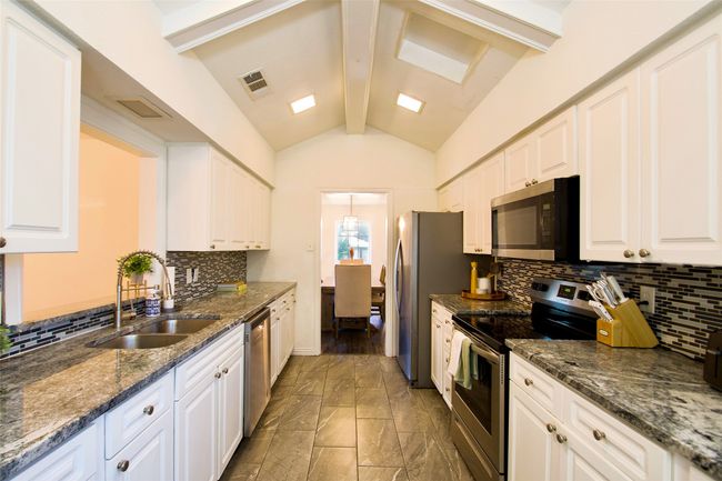 Kitchen with appliances with stainless steel finishes, light marble finish flooring, white cabinets, and backsplash | Image 10