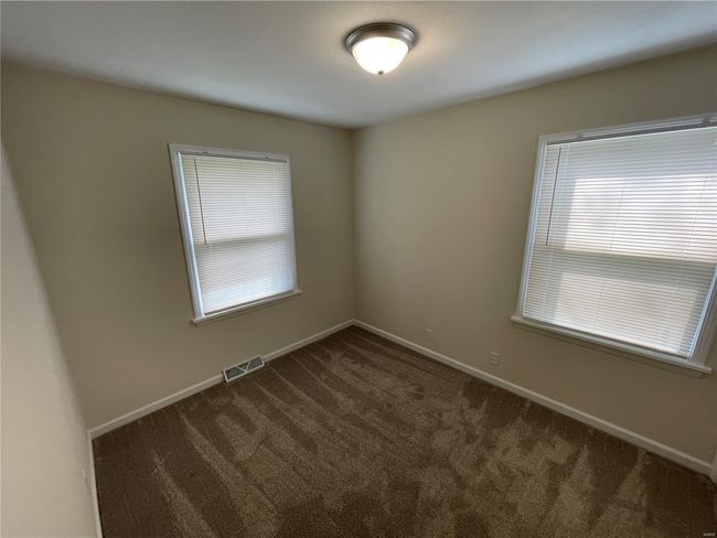 Spare room featuring baseboards, a healthy amount of sunlight, dark colored carpet, and visible vents | Image 26
