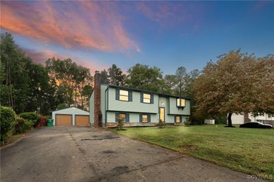 Bi-level home featuring a lawn, an outdoor structure, and a garage | Image 1