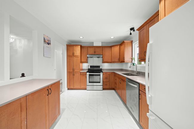 Kitchen with marble finish floor, stainless steel appliances, under cabinet range hood, a sink, and brown cabinetry | Image 6