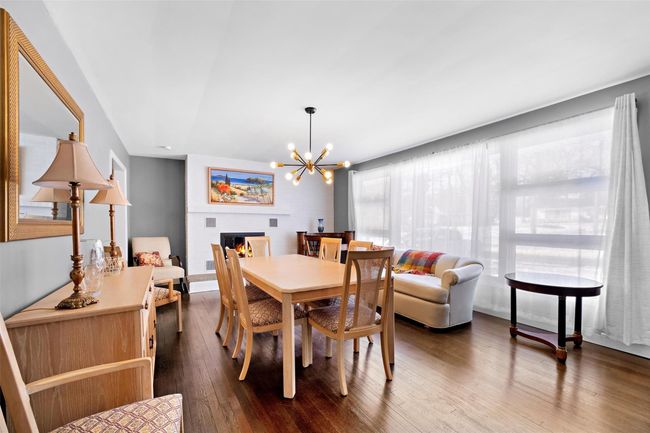 Dining area featuring dark wood-style floors, a glass covered fireplace, and a notable chandelier | Image 7
