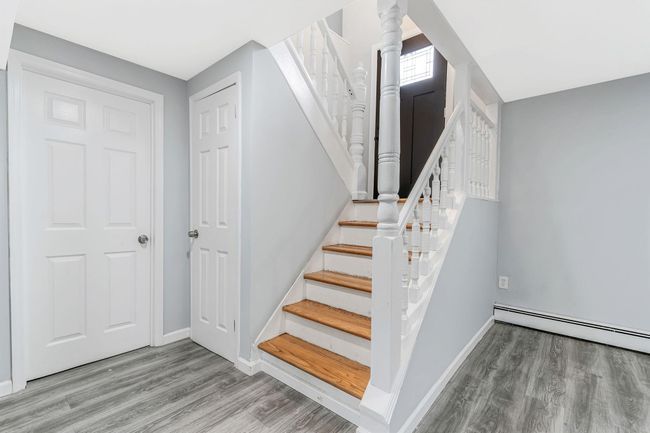 Staircase featuring baseboards, ornate columns, wood finished floors, and a baseboard heating unit | Image 15