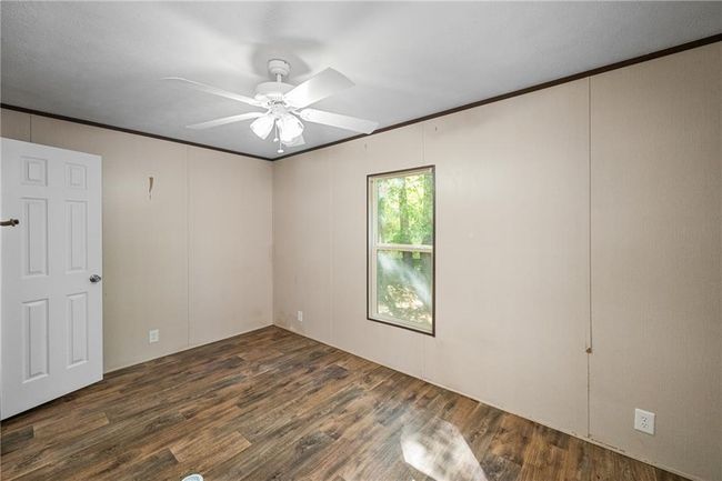 Spare room featuring ceiling fan, wood finished floors, and crown molding | Image 11