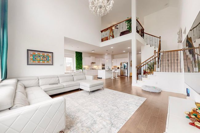 Living area with light wood-type flooring, a towering ceiling, a notable chandelier, and stairway | Image 7
