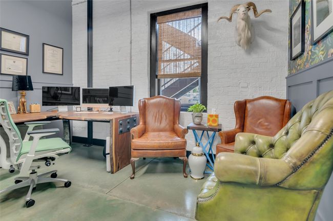 Home office featuring finished concrete floors and brick wall | Image 13