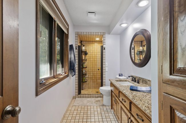 Private ¾ owner’s bath featuring ceramic tile floors, a dual tiled shower, ample storage, and a timeless, classy design. | Image 22