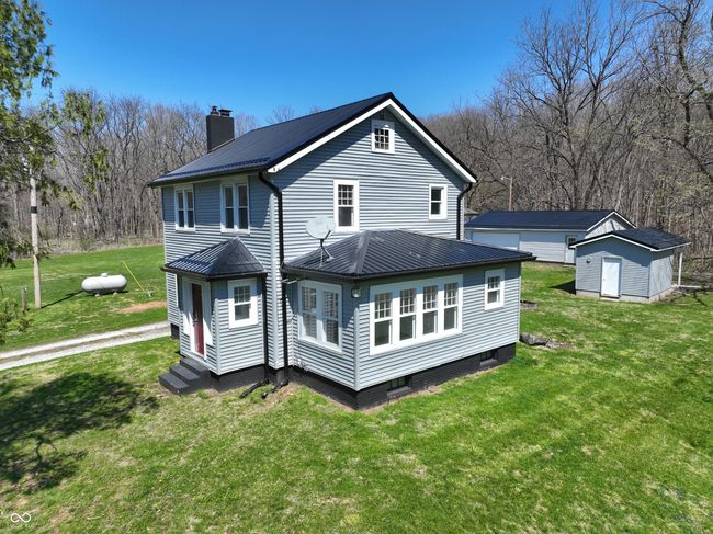 rear view of house featuring a chimney, metal roof, a standing seam roof, and an outbuilding | Image 6