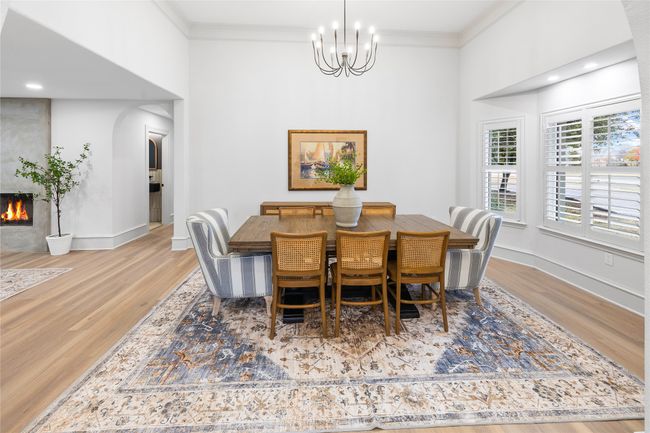 Dining area featuring arched walkways, a chandelier, crown molding, wood finished floors, and a towering ceiling | Image 10