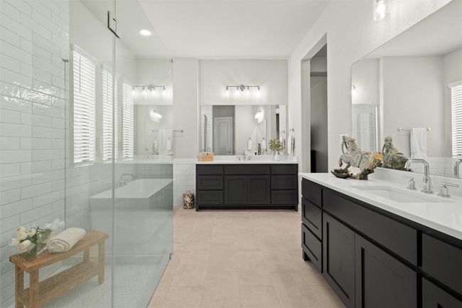 Full bath featuring two vanities, healthy amount of natural light, and a shower stall | Image 25