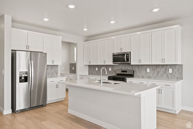 Kitchen with appliances with stainless steel finishes, a sink, light wood-style floors, white cabinetry, and tasteful backsplash | Image 13