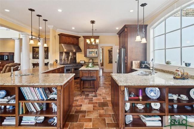 Shown from the breakfast area, the kitchen is a chef's delight. A 6 burner double oven with a griddle and pot filler, microwave, double dishwasher, and refrigerator make up the stainless steel package. | Image 10
