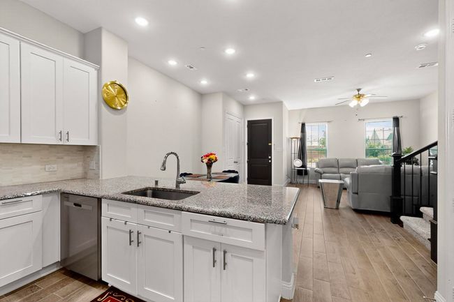 Kitchen featuring a peninsula, white cabinetry, light wood-style flooring, dishwasher, and a ceiling fan | Image 8