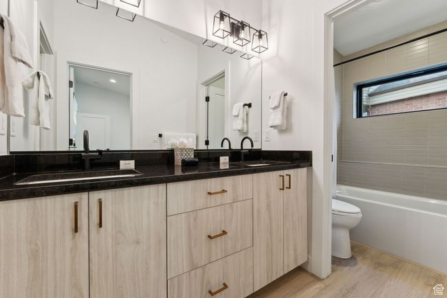 Full bathroom featuring toilet, vanity, tiled shower / bath combo, and hardwood / wood-style floors | Image 30