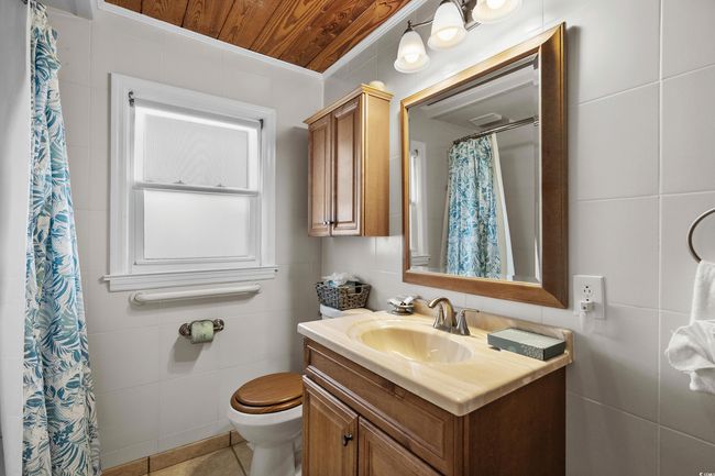 Full bath with vanity, toilet, wood ceiling, a shower with curtain, and tile patterned flooring | Image 35