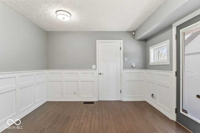 spare room with a decorative wall, dark wood-style flooring, a textured ceiling, and a wainscoted wall | Image 26