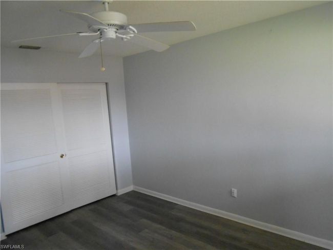 Unfurnished bedroom with ceiling fan, dark wood-style flooring, visible vents, baseboards, and a closet | Image 13