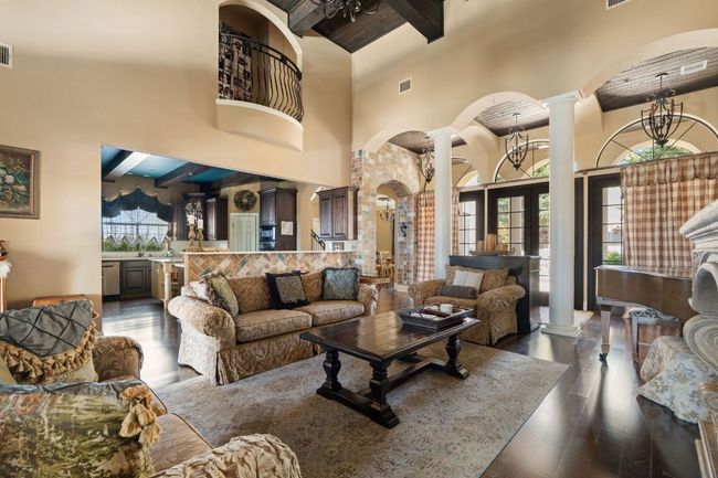 Living area with beam ceiling, arched walkways, decorative columns, and towering ceiling. | Image 10
