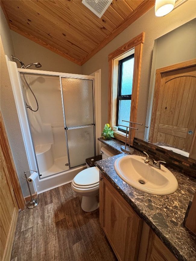 Bathroom with wood ceiling, vaulted ceiling, a stall shower, vanity, and wood finished floors | Image 33