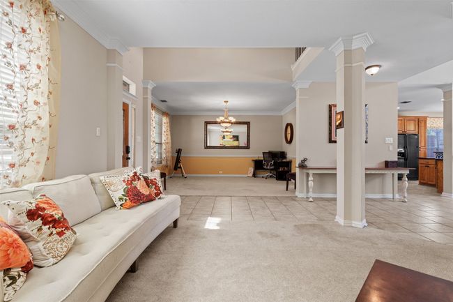 Living area with ornate columns, light tile patterned floors, light colored carpet, an office area, and crown molding | Image 6