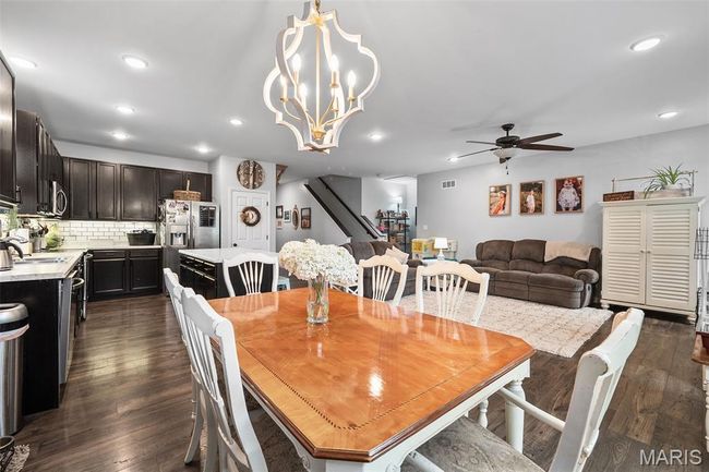 Dining space with a ceiling fan, dark wood-style flooring, recessed lighting, stairway, and a chandelier | Image 9