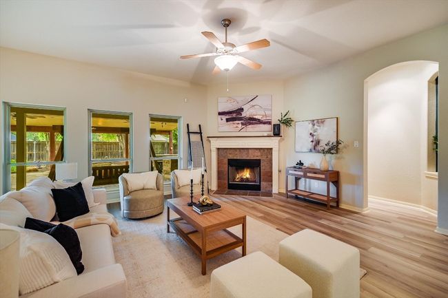 Living room featuring light wood-style flooring, arched walkways, a tiled fireplace, and ceiling fan | Image 17