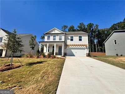 View of front facade with a front lawn, a porch, and a garage | Image 1