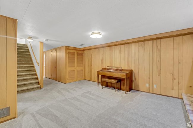Finished below grade area featuring light colored carpet, stairs, and wooden walls | Image 19
