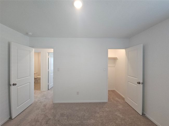 Unfurnished bedroom featuring carpet floors, a spacious closet, baseboards, and a closet | Image 13