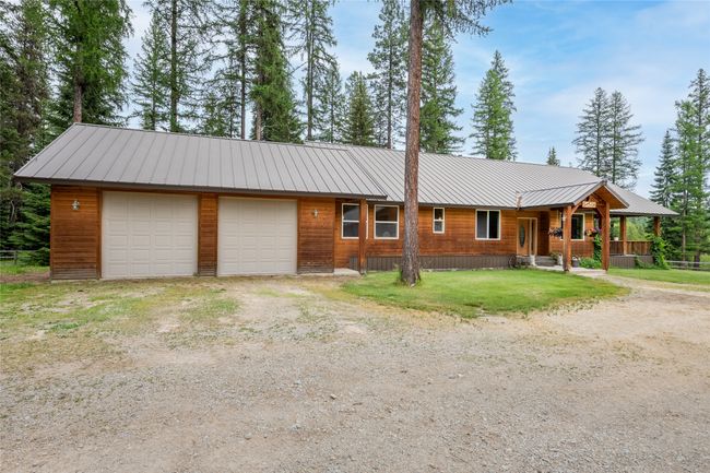 View of front of home with a metal roof, dirt driveway, covered porch, and a front lawn | Image 20