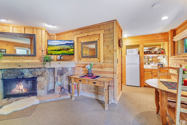 Interior space featuring wood walls, light colored carpet, a stone fireplace, and recessed lighting | Image 41
