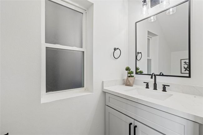 A beautifully designed vanity with ample storage, complemented by chic lighting and a frosted window for privacy and natural light. | Image 8