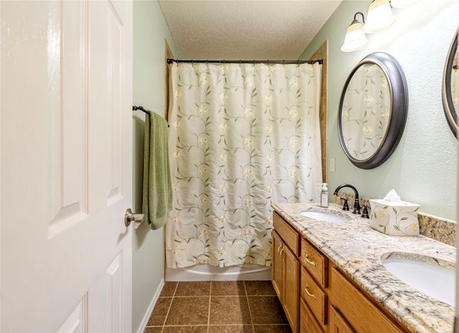Full bathroom with double vanity, tile patterned flooring, a textured ceiling, and shower / tub combo | Image 30