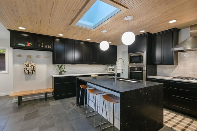 Kitchen featuring skylight and quartz countertops and quartzite waterfall island | Image 13