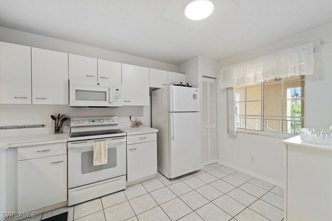 Kitchen with baseboards, white appliances, light countertops, light tile patterned flooring, and white cabinets | Image 7