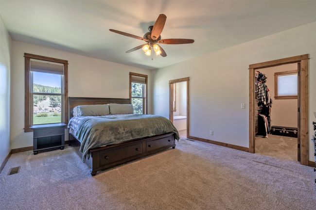 Bedroom with carpet floors, a walk in closet, baseboards, a ceiling fan, and connected bathroom | Image 16