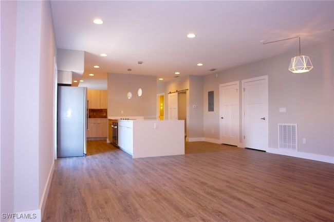 Unfurnished living room featuring a barn door, recessed lighting, light wood-style flooring, and electric panel | Image 4