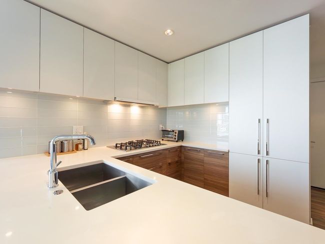 Kitchen featuring backsplash, light countertops, stainless steel gas stovetop, modern cabinets, and white cabinetry | Image 5