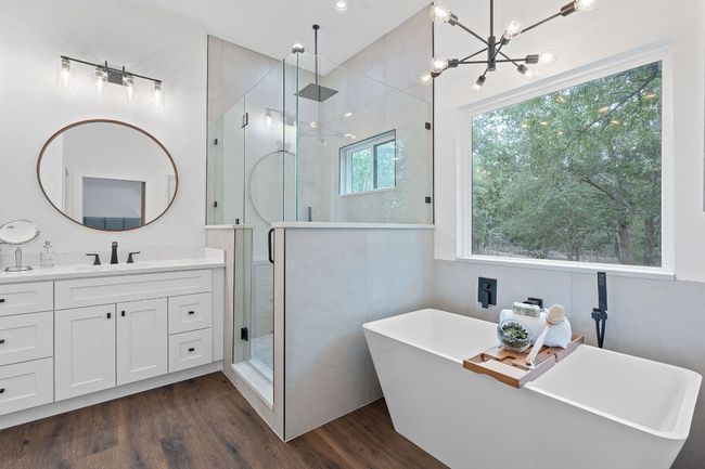Bathroom featuring a freestanding soaking tub, a walk-in shower, dual vanity, and a notable chandelier | Image 29