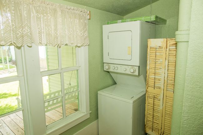 Laundry room with estacked washer and dryer, a textured wall, and healthy amount of natural light | Image 19