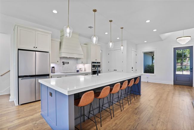Kitchen with light wood finished floors, stainless steel appliances, tasteful backsplash, custom exhaust hood, and recessed lighting | Image 12