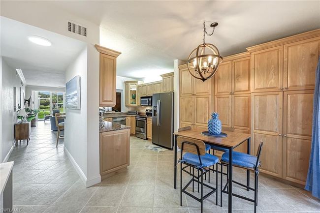 Kitchen with appliances with stainless steel finishes, a chandelier, dark stone countertops, decorative light fixtures, and light tile patterned floors | Image 5