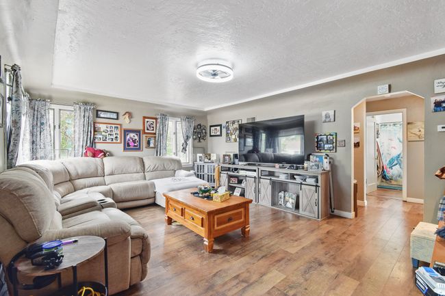 Living room featuring a textured ceiling, arched walkways, hardwood / wood-style flooring, and baseboards | Image 6