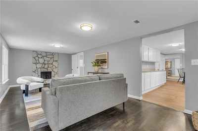 Living room with a stone fireplace, dark hardwood / wood-style flooring, and a textured ceiling | Image 3